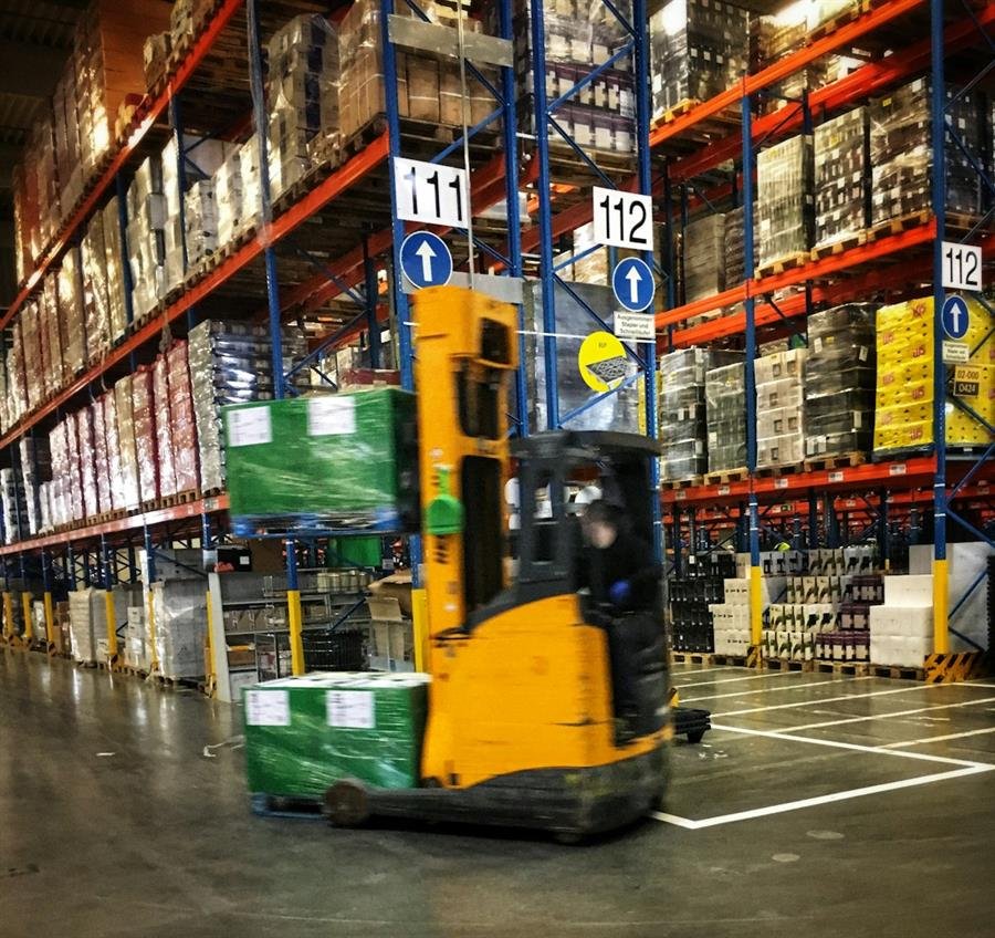 Forklift moving through a warehouse with pallet storage