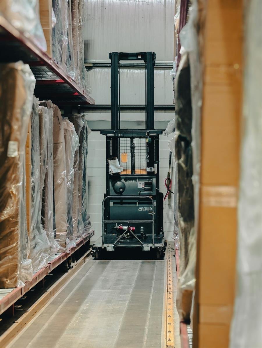 Forklift parked in a narrow warehouse aisle between pallet racks