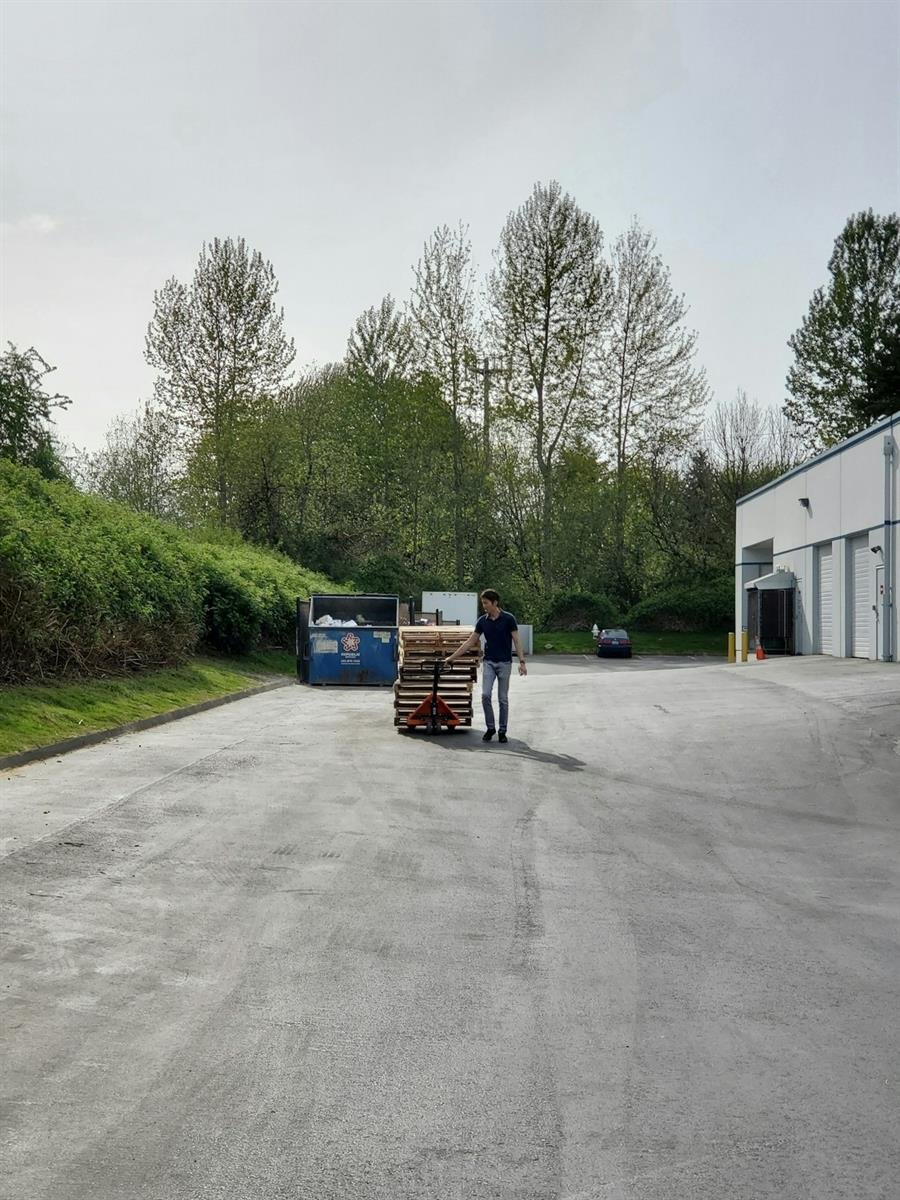 Worker moving pallets with a manual pallet jack
