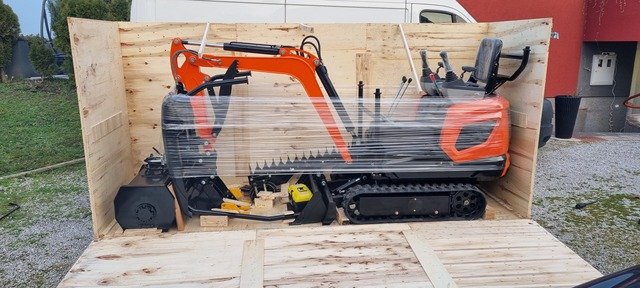 An orange mini excavator secured in an open wooden packing case.