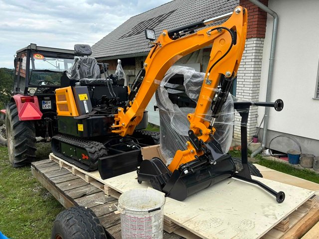 A yellow mini excavator and separately wrapped attachments on a wooden base.